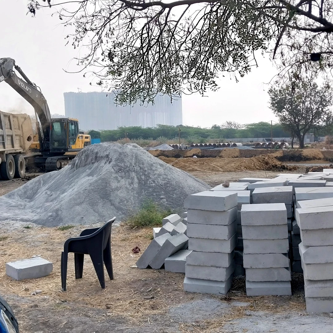 Block Staging Concrete blocks and construction aggregates staged in the foreground while heavy machinery operates in the background at Prestige Golden Grove