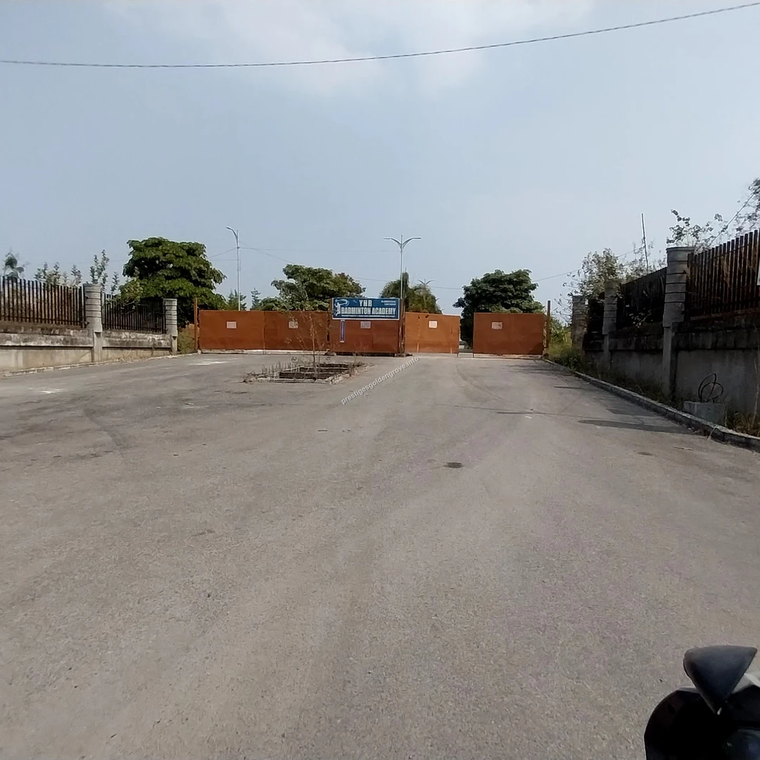 Site Entrance View Wide angle view of the entrance road and main gate leading to the Prestige Golden Grove project site in Hyderabad